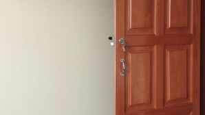 A room with a wooden door, a mounted television, and a green wall. - HOSTAL ETERNA PRIMAVERA  (Copacabana)