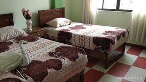 A room with two beds, each with floral-patterned bedding and pillows. There is a vase with flowers on a nightstand between the beds. - HOSTAL ETERNA PRIMAVERA  (Copacabana)