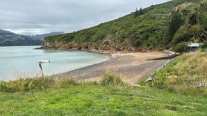 Ein Strand mit einem Boot, das an der Küste liegt, umgeben von üppiger Vegetation und Hügeln im Hintergrund.
