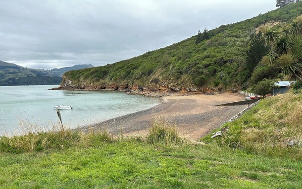 Enjoy a serene coastal escape with a gentle beach slope, lush greenery, and a tranquil sea view.
