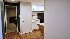 A compact kitchen with white cabinets, a black refrigerator, and a wooden countertop.