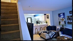 A living room with a sofa, a coffee table, and a staircase leading to another room.