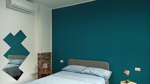 Et soveværelse med en seng, et natbord, en lampe og et lille bord med en vase.
