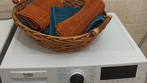 En frontbetjent vaskemaskine med en kurv foldede håndklæder ovenpå.