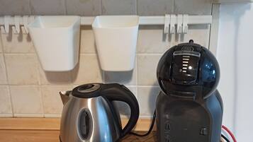 Eine Küche mit Wasserkocher, Kaffeemaschine und einem Teller Essen auf einer Matte.