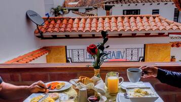 A dining table set with breakfast items, including a bowl of pasta, a plate of sliced bananas, and a glass of orange juice.