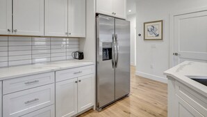 A modern kitchen with white cabinetry, a stainless steel refrigerator, and a tiled backsplash.