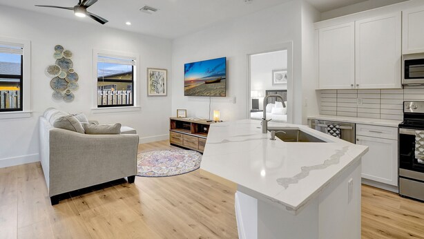 A modern kitchen with white cabinetry, a central island, and a ceiling fan.