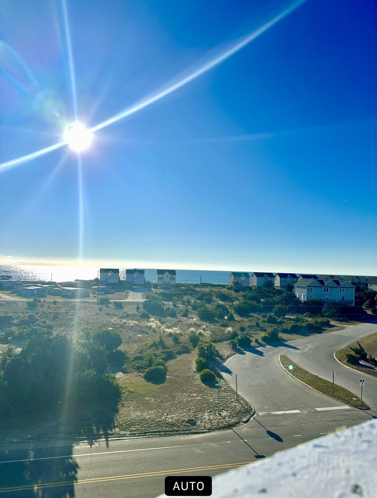Uma estrada costeira com vista clara para casas e uma praia ao longe.