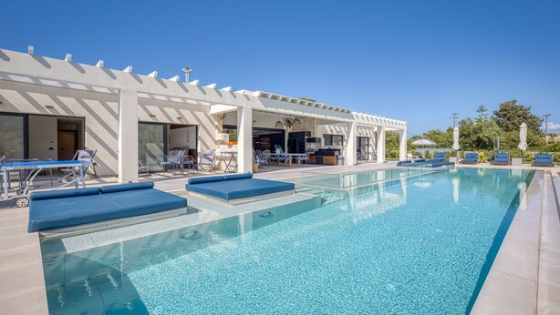 Une piscine avec des chaises longues et un patio couvert.