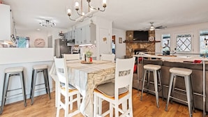 A modern kitchen with a central island, bar stools, and a chandelier. - Lazy Bear Lodge-Breathtaking Views! Pet Friendly (Maggie Valley)