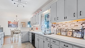 A modern kitchen with grey cabinets, a built-in oven, and a large window. - Lazy Bear Lodge-Breathtaking Views! Pet Friendly (Maggie Valley)