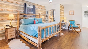 A bedroom with a wooden bed, a ceiling fan, and a rocking chair. - Lazy Bear Lodge-Breathtaking Views! Pet Friendly (Maggie Valley)