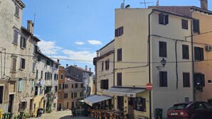A cobblestone street with buildings, a café with outdoor seating, and a parked car. - MARE FUORI - Studio Apartment with Terrace (Rovinj)