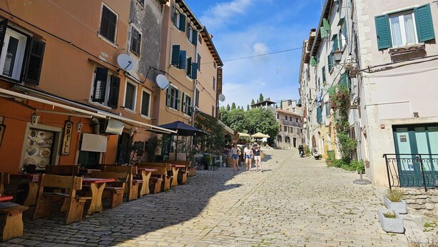 A cobblestone street lined with traditional buildings, outdoor seating, and a restaurant with a signboard. - MARE FUORI - Studio Apartment with Terrace (Rovinj)