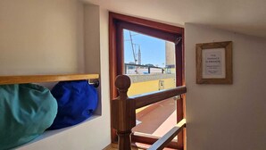 A room with a wooden bench, a window with a view of a building, and a framed sign on the wall. - MARE FUORI - Studio Apartment with Terrace (Rovinj)