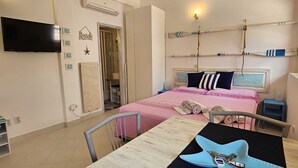 A bedroom with a bed, a TV, a table with a starfish-shaped object, and a wardrobe. - MARE FUORI - Studio Apartment with Terrace (Rovinj)