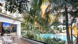 An indoor pool area with a view of a mountain, surrounded by lush greenery and modern outdoor furniture. - BRAND NEW! 2BR Apt near Disney and SNA! Pool & Gym
 (Santa Ana)