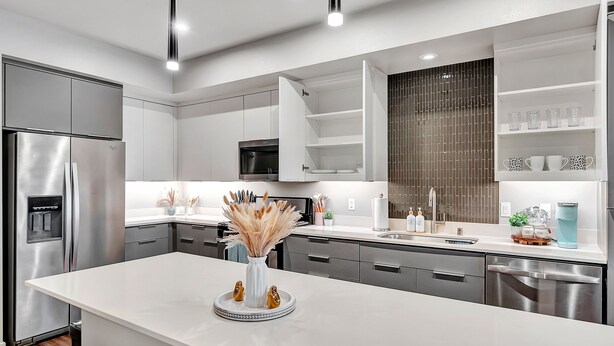 A modern kitchen with white cabinetry, stainless steel appliances, and a central island with decorative items. - BRAND NEW! 2BR Apt near Disney and SNA! Pool & Gym
 (Santa Ana)