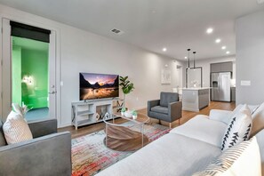 A modern living room with a sofa, armchair, and a TV on a stand.