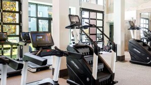 A gym with treadmills and stationary bikes, large windows, and a high ceiling. - BRAND NEW! 2BR Apt near Disney and SNA! Pool & Gym
 (Santa Ana)