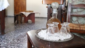 Ein Holztisch mit einem Glaskarafell und vier kleinen Gläsern auf einer Spitzendecke.