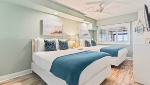 Un dormitorio con dos camas, ventilador de techo y obras de arte en las paredes.