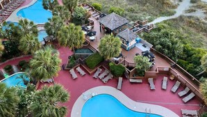 Un resort con varias piscinas, zonas de estar al aire libre y vista al mar.
