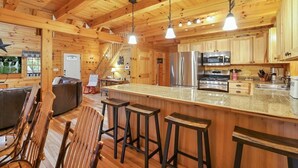 Een ruime keuken met houten kastjes, een groot eiland met barstoelen en moderne apparatuur.