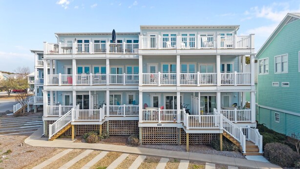 A multi-story beachfront hotel with balconies, a pool area, and a view of the ocean.