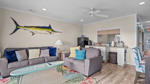 A living room with a grey sofa, a coffee table, and a large fish mural on the wall.