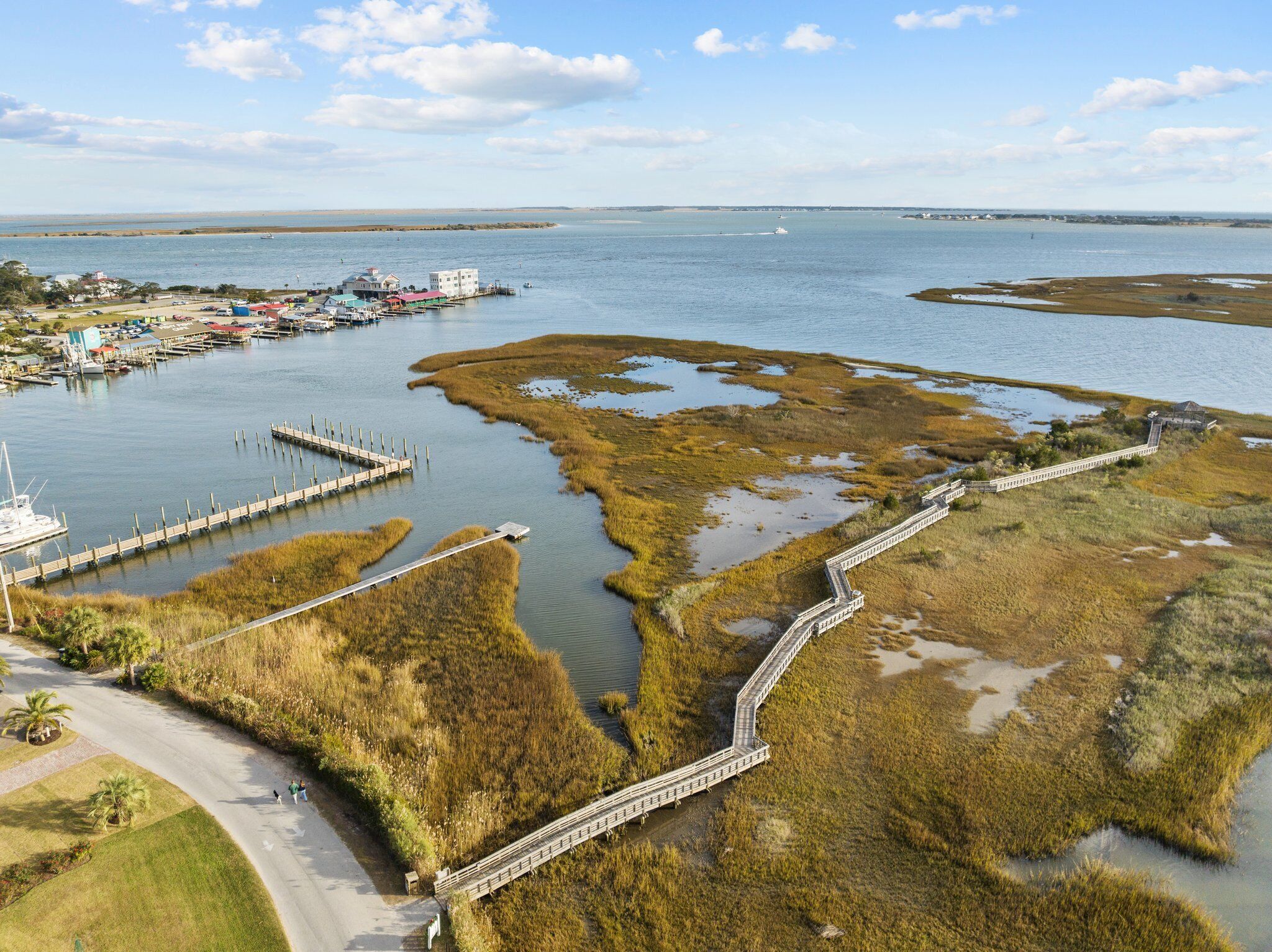 An aerial view of a coastal area with a marina, a bridge, and a boardwalk.