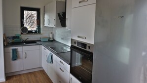 A modern kitchen with white cabinets, stainless steel appliances, and a window above the sink.