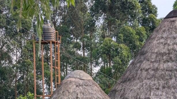 A thatched-roof hut with a wooden door and a small table with chairs in front. - White Cat Farm Hut Inn (Mashonga)