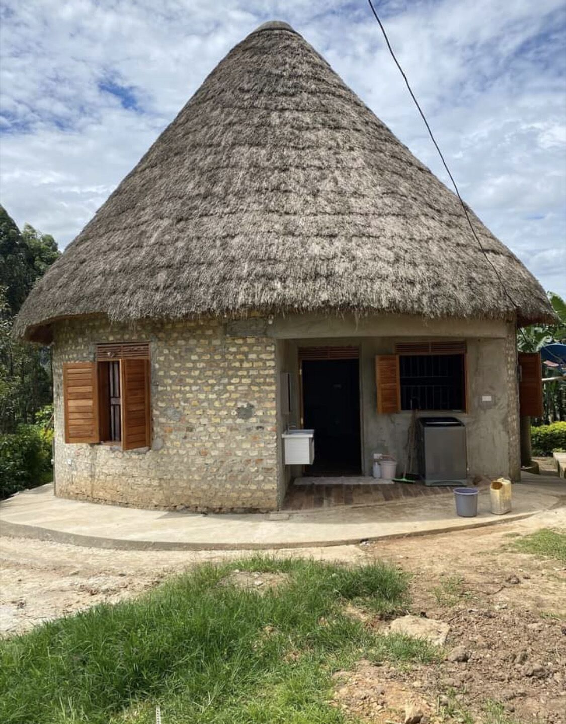 A thatched-roof house with a stone exterior, a small porch, and a single door.