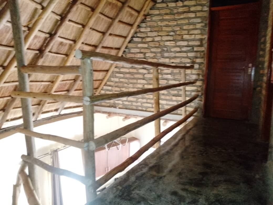 Una habitación con techo de paja, pared de ladrillo y puerta de madera.