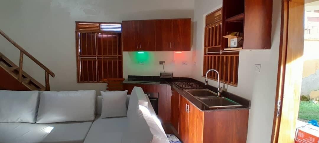 Un espacio habitable compacto con kitchenette, un sofá y una escalera.