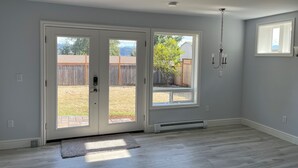 A spacious room with a large sliding glass door leading to a backyard, a ceiling-mounted light fixture, and a small window on the wall.