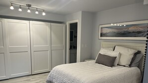 A bedroom with a bed, a nightstand, a wardrobe, and a painting on the wall.