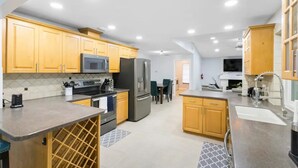 Una cucina moderna con mobili in legno, elettrodomestici in acciaio inossidabile e una cantinetta per vini integrata.