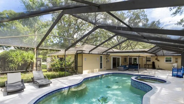 Una piscina scoperta coperta con sedie a sdraio e un patio coperto.