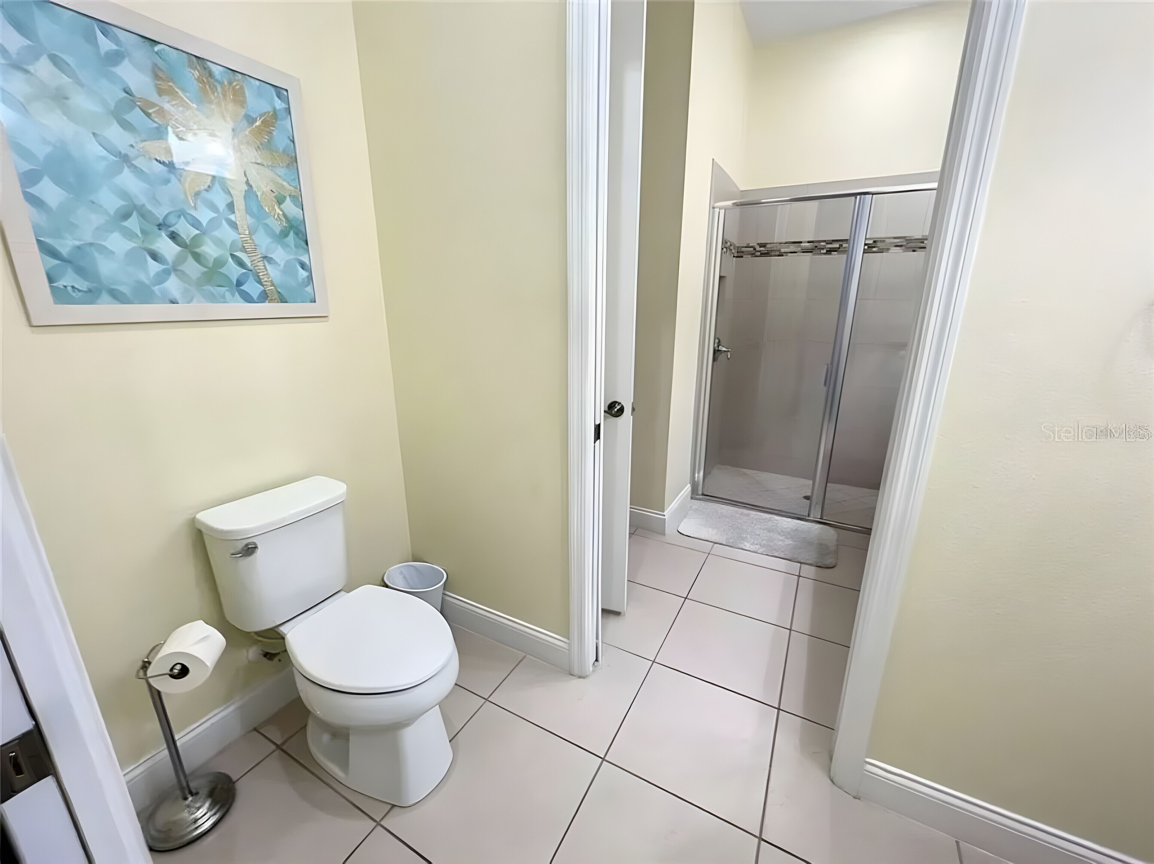 Bany amb vàter, bidet, dutxa i un quadre al mur.
