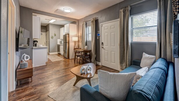 En moderne stue med en blå sofa, et sofabord og et spiseområde med et bord og stole.