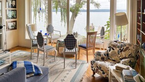 Una habitación acogedora con un ventanal grande que da a un lago, amueblada con un sofá, sillas y una mesa.