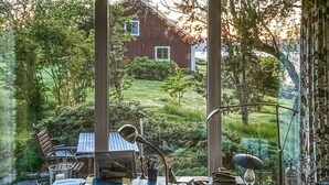 Una habitación con escritorio, silla y vistas a una casa de ladrillo rojo a través de una ventana.