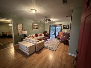 A living room with a sofa, armchair, and ottoman, a ceiling fan, and a door leading to a patio. - Spacious home.  Close to LSU, shopping, hospitals, downtown.  Pets welcome. (Baton Rouge)