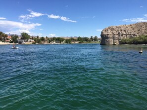 A lake with a rocky outcrop on the right, a jet ski on the left, and buildings along the shore. - VIEW, NEWER HOME NEAR COLORADO RIVER, GOLF, SHOPPING, ATV TRAILS (Fort Mohave)