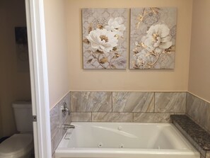 A bathroom with a bathtub, two wall-mounted floral paintings, and marble tiles. - VIEW, NEWER HOME NEAR COLORADO RIVER, GOLF, SHOPPING, ATV TRAILS (Fort Mohave)