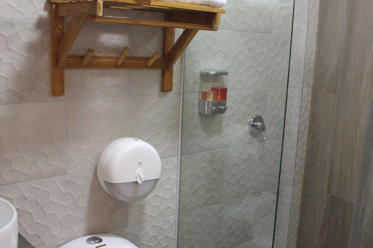 A modern bathroom with a toilet, a glass-enclosed shower, and a towel rack.