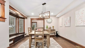 A dining area with a wooden table and chairs, a chandelier, and a clock on the wall.